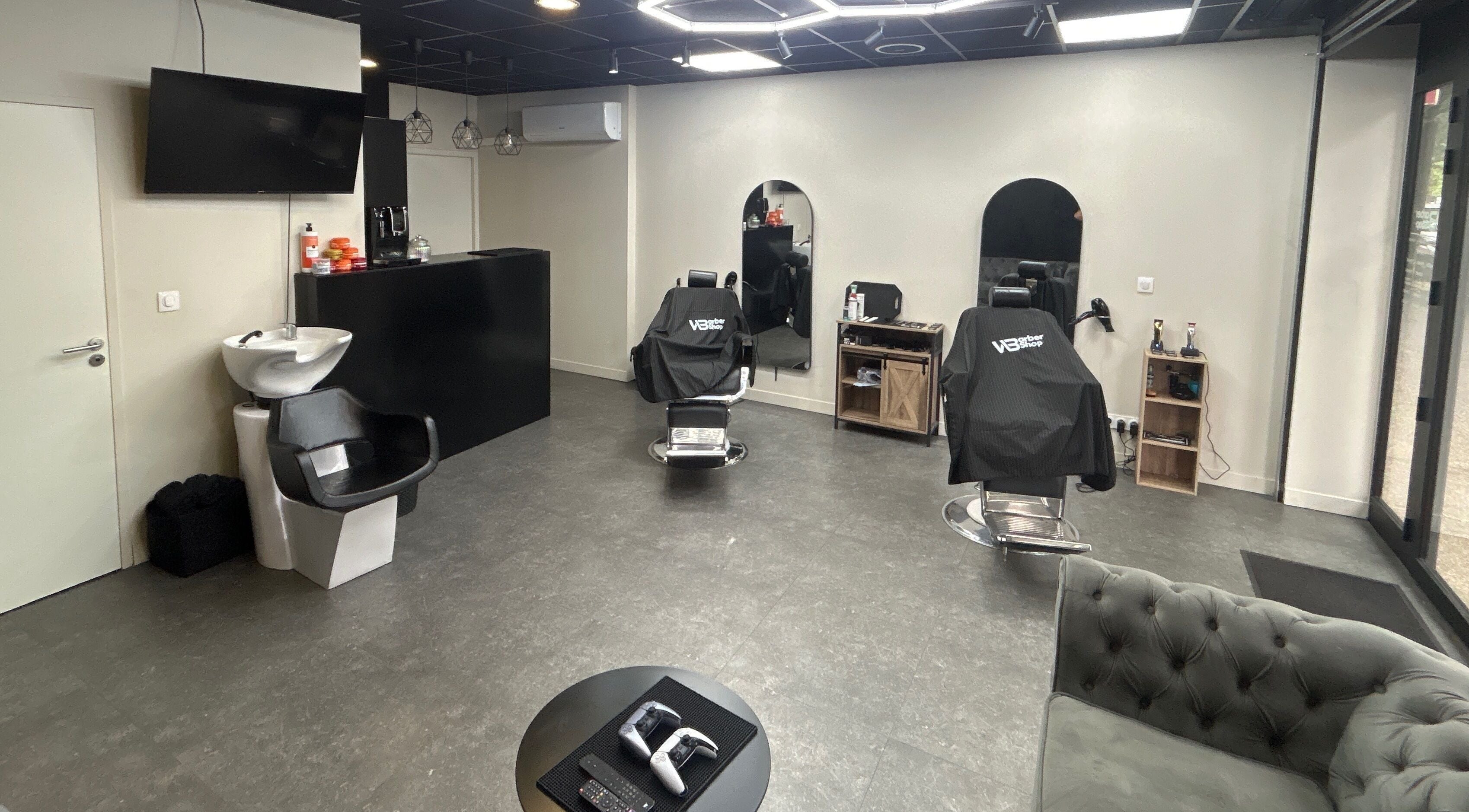 Intérieur moderne de Wbarbershop à Échirolles, Auvergne-rhône-alpes, FR avec fauteuils de coiffure noirs.