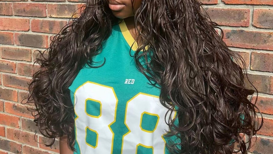 Lush, curly hair styled at Naomiscrownedtouch, London, England, GB against a brick wall.