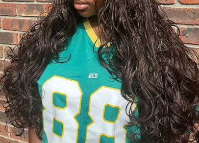 Lush, curly hair styled at Naomiscrownedtouch, London, England, GB against a brick wall.