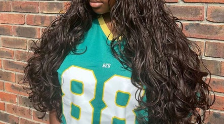 Lush, curly hair styled at Naomiscrownedtouch, London, England, GB against a brick wall.