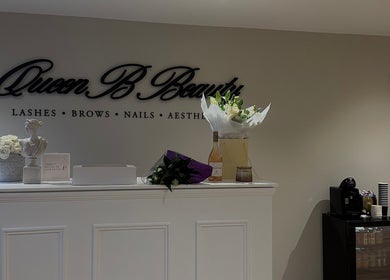 Reception area at Queen B Beauty in Newhaven, England, GB, showcasing a stylish setup with flowers and decor.