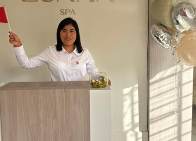 Receptionist at Luana Spa, Carmen De La Legua - Reynoso, Callao, PE, smiling with balloons and a small flag.