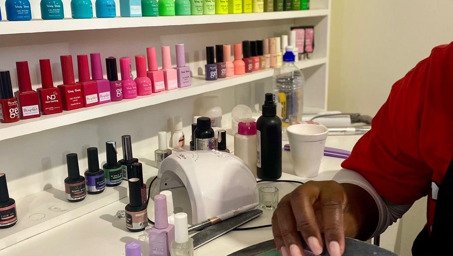 A vibrant display of nail polishes at NailedbyStheM, Soweto, Gauteng, ZA, showcasing being applied by a skilled hand.