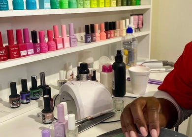 A vibrant display of nail polishes at NailedbyStheM, Soweto, Gauteng, ZA, showcasing being applied by a skilled hand.