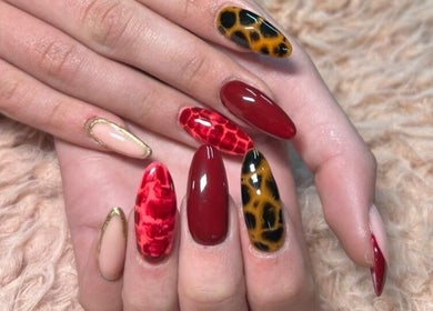 Detailed nail art at Bloom & Thrive Beauty, Parys, Free State, ZA. Red and gold nail designs create a dynamic look.