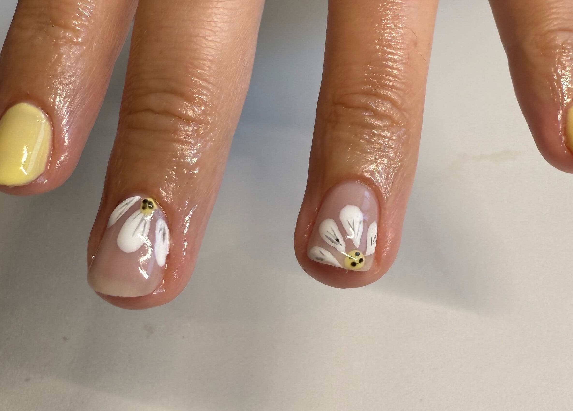 Elegant floral nail art at Esthetics by Sydney, South Glengarry, Ontario, CA. Vibrant yellow and white design.