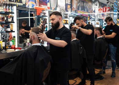 Barber expertly cutting hair at Moe & Co West Gosford, West Gosford, New South Wales, AU. Vibrant salon atmosphere.