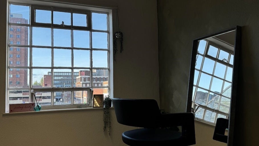 Serene salon chair by large window at SHADE TWENTY2, Wolverhampton, England, GB. Urban views provide a calming backdrop.