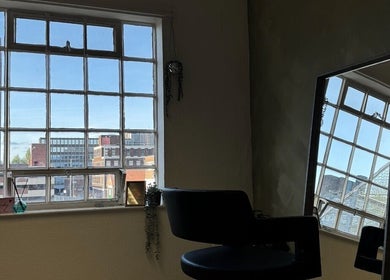 Serene salon chair by large window at SHADE TWENTY2, Wolverhampton, England, GB. Urban views provide a calming backdrop.