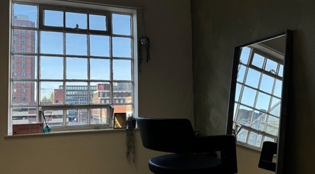 Serene salon chair by large window at SHADE TWENTY2, Wolverhampton, England, GB. Urban views provide a calming backdrop.