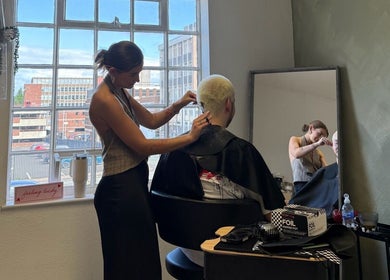 Stylist at Studio Shade Wlv in Wolverhampton, England, GB, cutting a client's hair by a window.