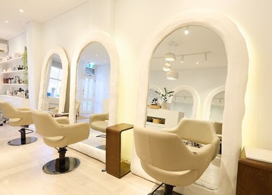 Modern salon interior at Hair by Rhie, Surry Hills, New South Wales, AU with stylish chairs and mirrors.