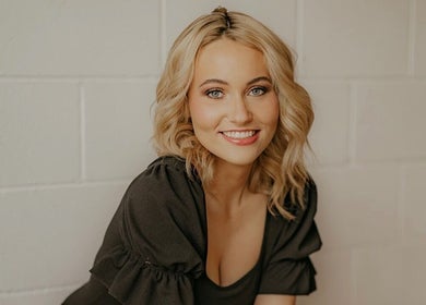 Smiling woman at SDZ Hair Loft, Dublin, Ohio, US, showcasing a styled blonde look with soft waves.