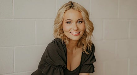 Smiling woman at SDZ Hair Loft, Dublin, Ohio, US, showcasing a styled blonde look with soft waves.