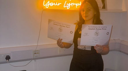 Individual holding certificates at vibrantSculpt in Knowsley, England, GB showcasing achievement.