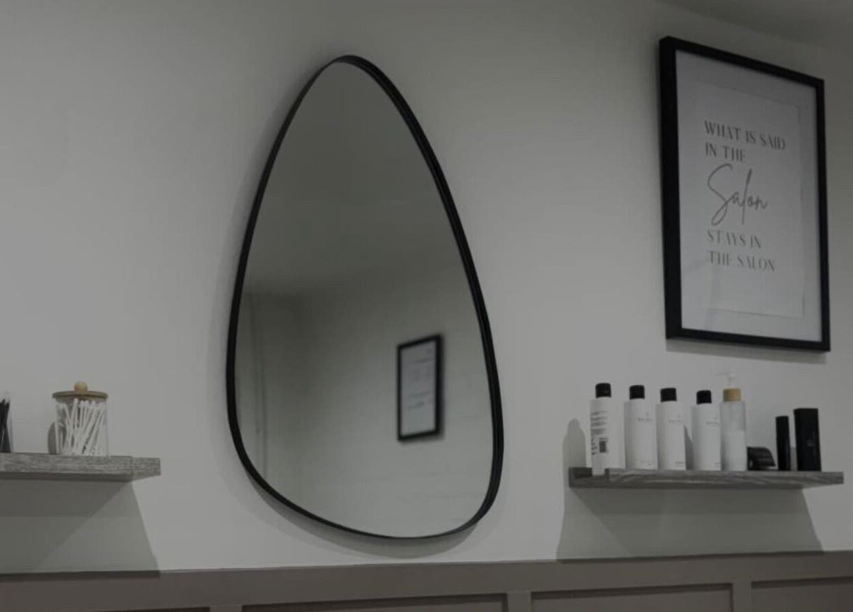 Modern salon setup at Studio.19 in Ixworth, England, featuring a unique teardrop mirror and beauty products.