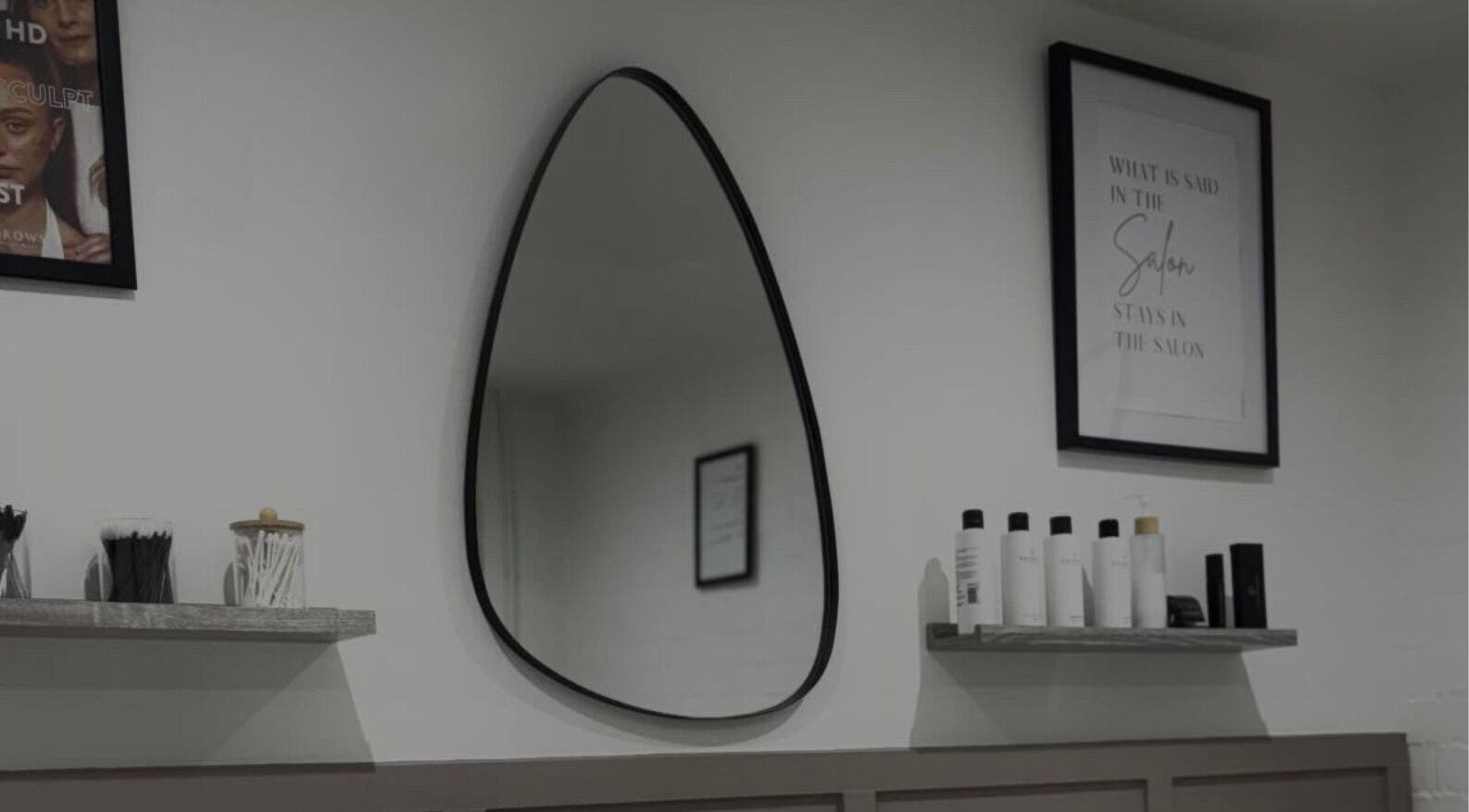 Modern salon setup at Studio.19 in Ixworth, England, featuring a unique teardrop mirror and beauty products.