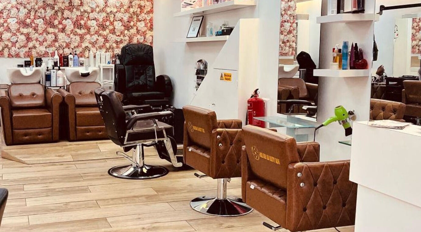 Stylish interior of Ariel Hair & Beauty in London, England, GB showing salon chairs and floral wall decor.