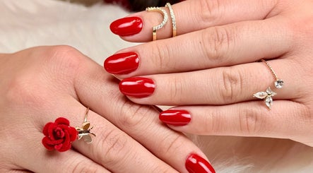 Manicura roja vibrante en Nail Studio, Lleida, Catalunya, ES. Las manos delicadamente adornadas con joyas.