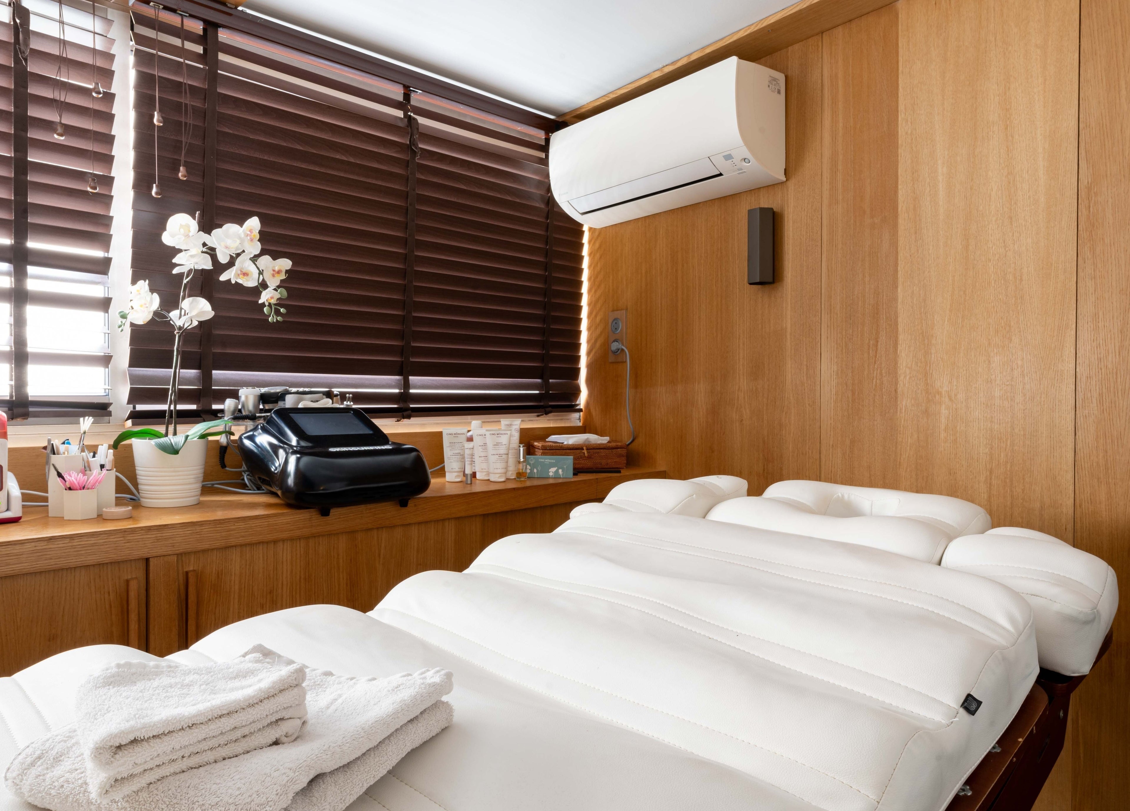 Salle de soins moderne à BCBG Paris, Paris, Île-de-France, FR avec lit de massage et orchidée.