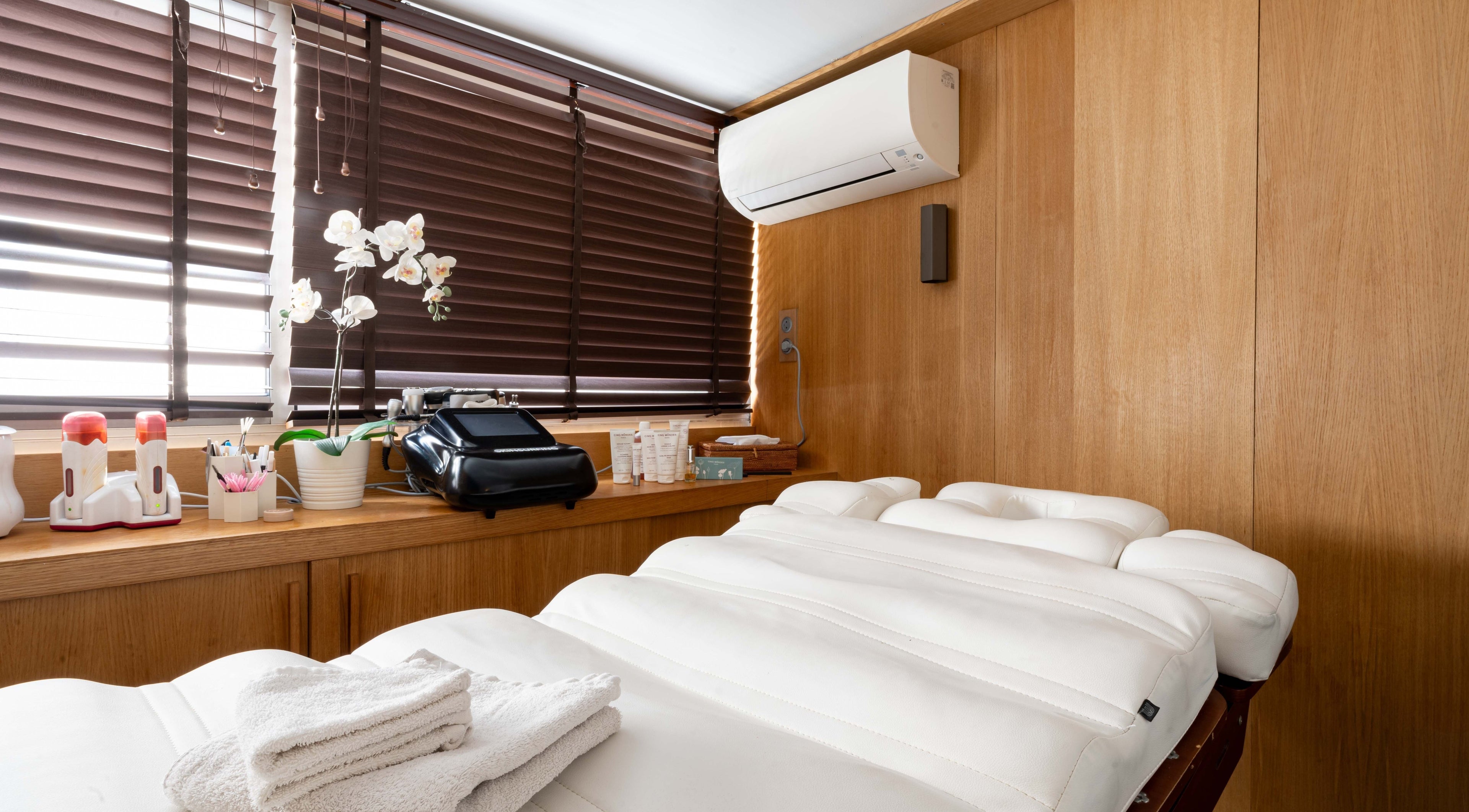 Salle de soins moderne à BCBG Paris, Paris, Île-de-France, FR avec lit de massage et orchidée.