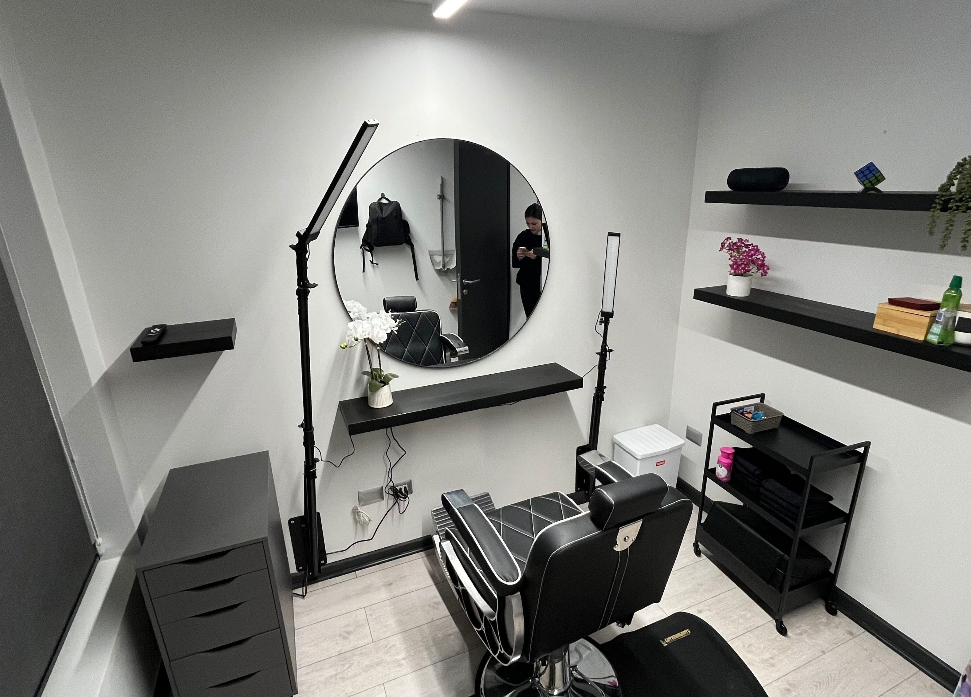 Salón moderno en VIBRA STUDIO, Concepción, Bío Bío, CL, con silla de barbero y espejo redondo.