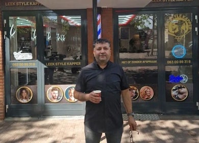Owner standing outside Leek Style Kapper in Leek, Groningen, NL on a sunny day.