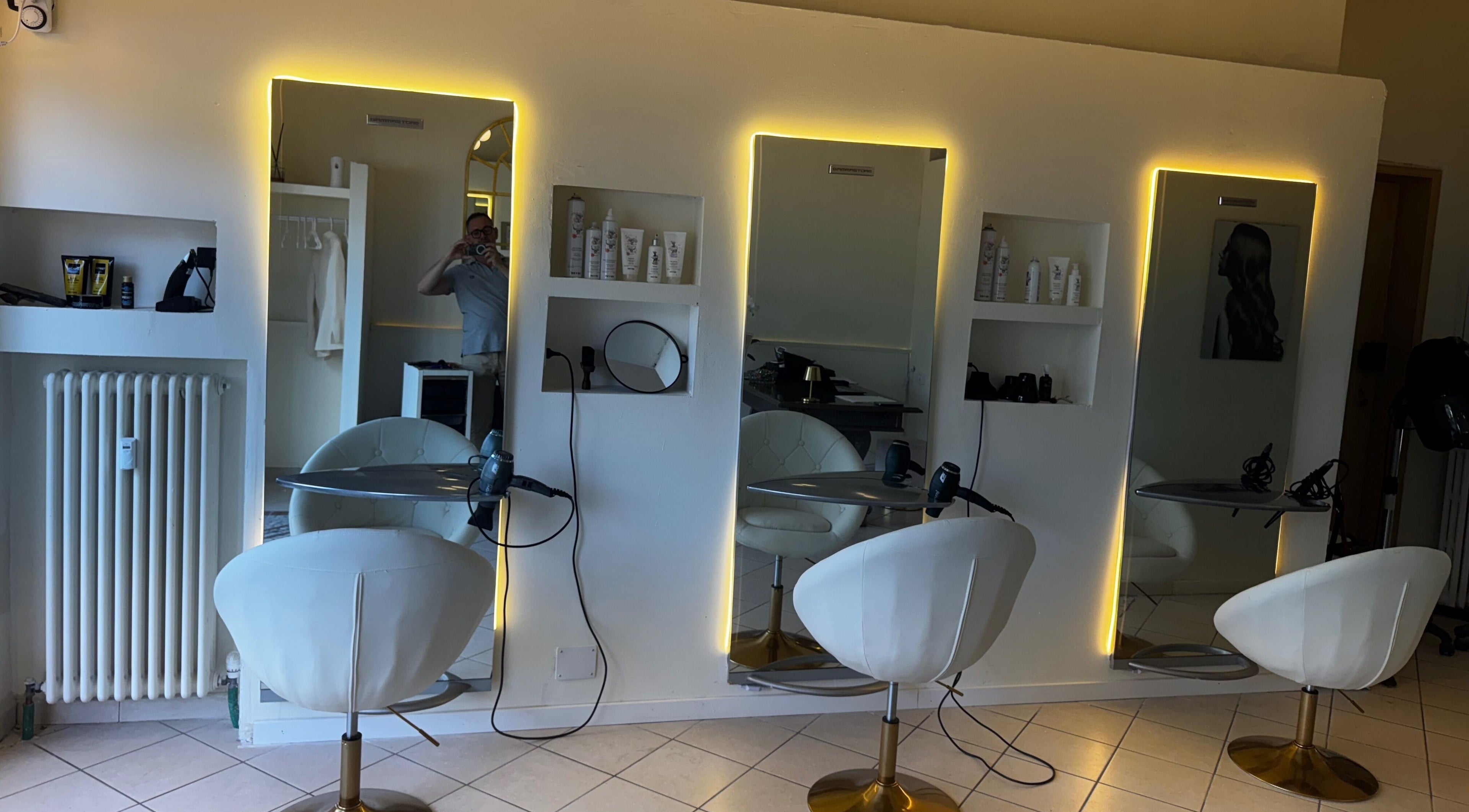 Interno luminoso di Kioma a Casale Monferrato, Piemonte con poltrone moderne e specchi illuminati.