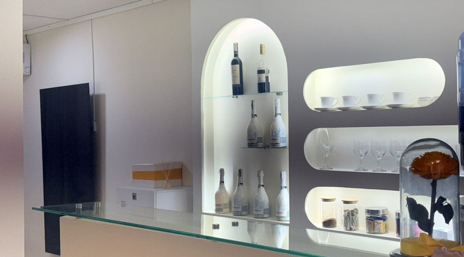 Estantería elegante en Belleza Integral Avanzada, Cali, Valle Del Cauca, CO, mostrando botellas y tazas.