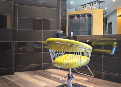 Modern yellow salon chair at Seoul Hair salon in Calgary, Alberta, CA with sleek black and wood decor.