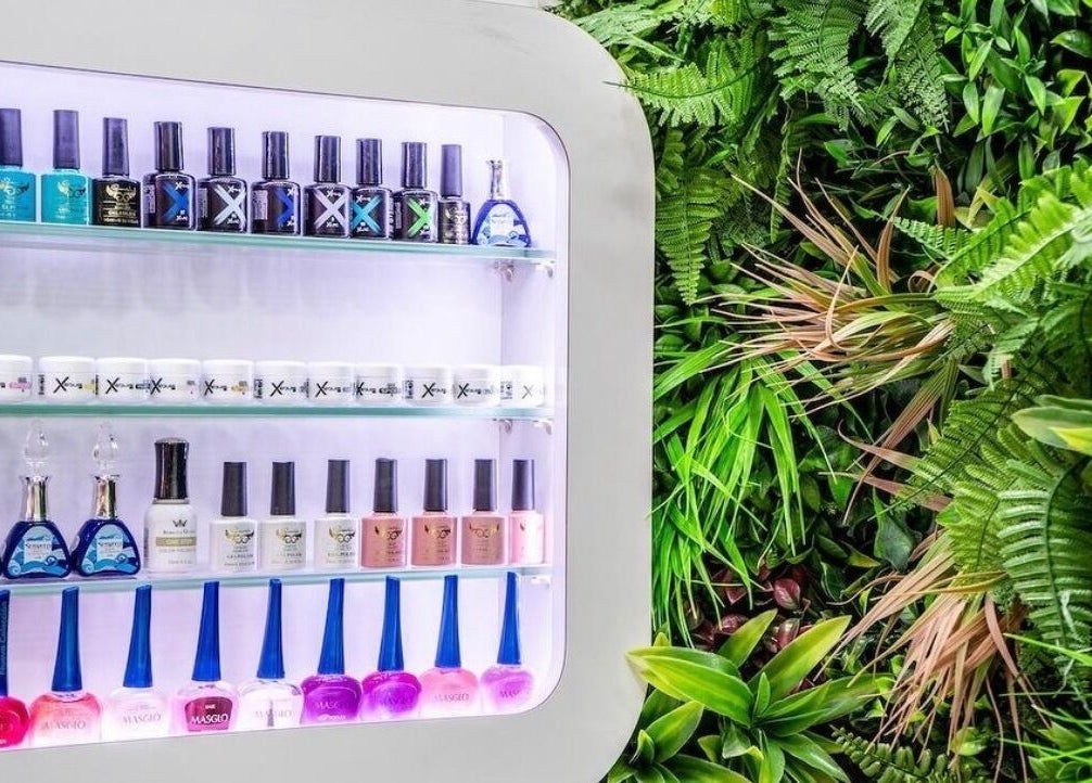 Estante de esmaltes en WOW Nails Getafe, Getafe, Comunidad De Madrid, ES, frente a pared vegetal.