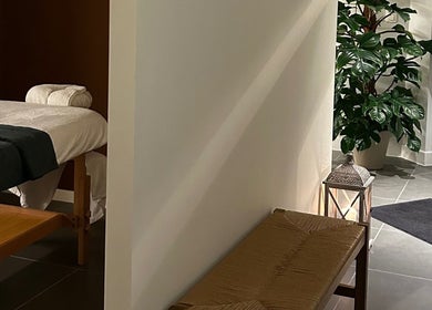 Relaxing massage room at Sureechai Massages in Hove, Vlaanderen, BE with a massage bed and lush plant.