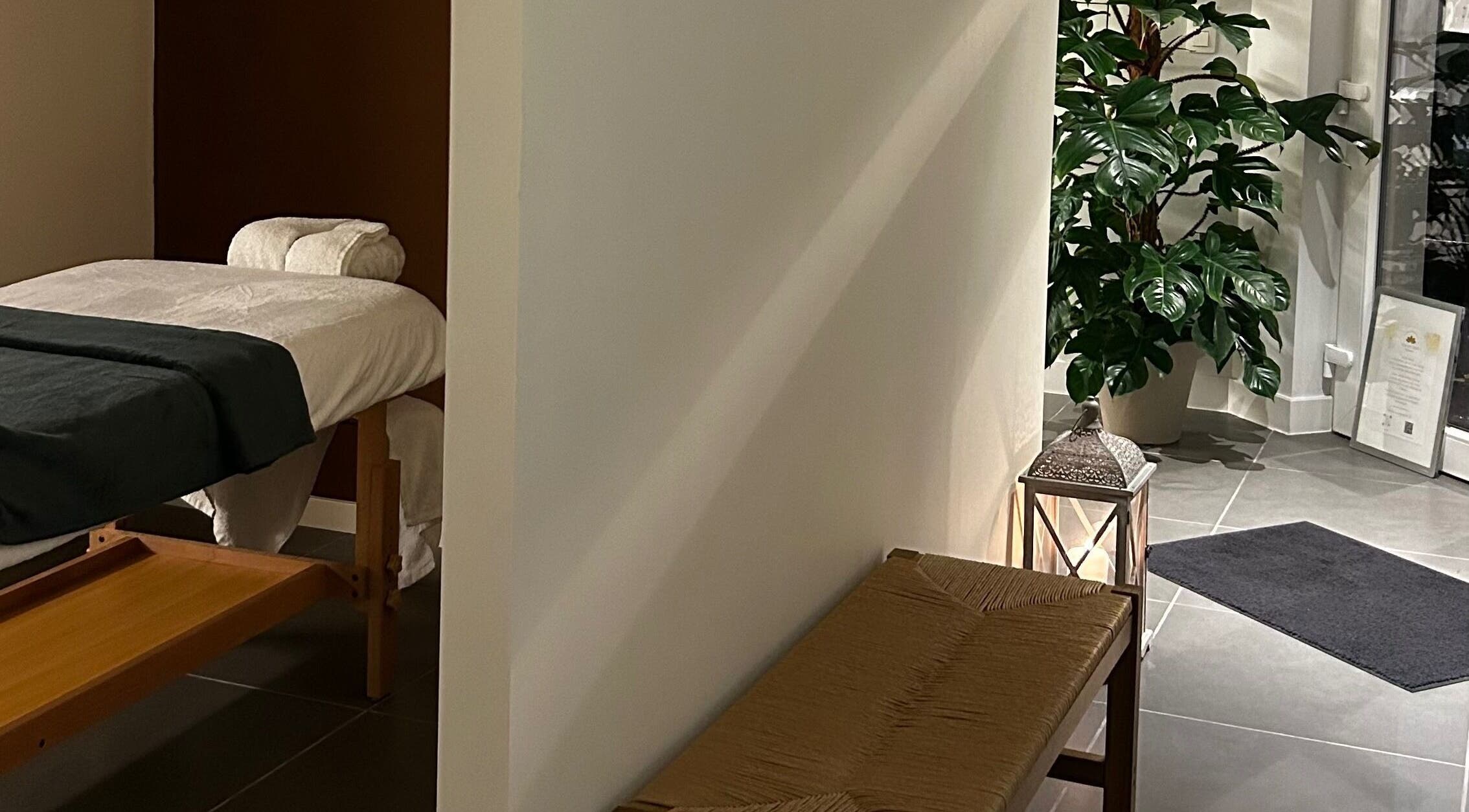 Tranquil massage room at Sureechai Massages, Hove, Vlaanderen, BE, featuring a comfortable massage table and lush greenery.