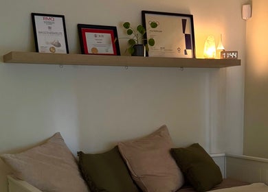 Cozy relaxation area at Em-Bodywellness, Montréal, Québec, CA with pillows and softly lit shelf decor.
