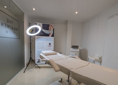 Relaxing treatment room at Refine Aesthetics by Ella, Brighton, England, GB with white treatment bed and lighting.