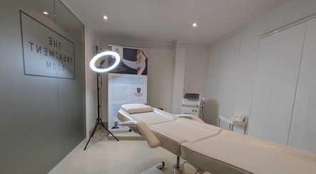 Relaxing treatment room at Refine Aesthetics by Ella, Brighton, England, GB with white treatment bed and lighting.