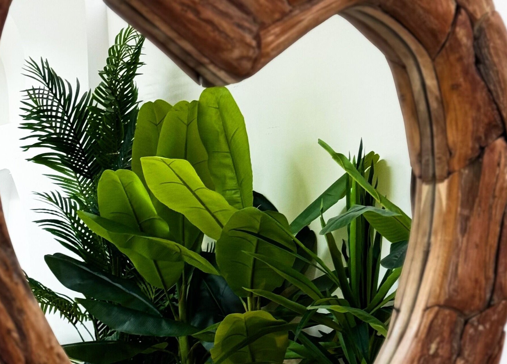Rustic mirror at De Palma Nail Spa, Makkah, SA, reflecting vibrant green plants for a tranquil atmosphere.