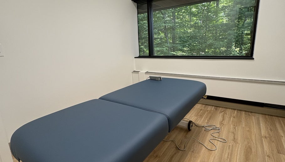 Relaxing massage room at Xiomara Wellness Massage in Avon, Connecticut, US with a view of lush greenery.