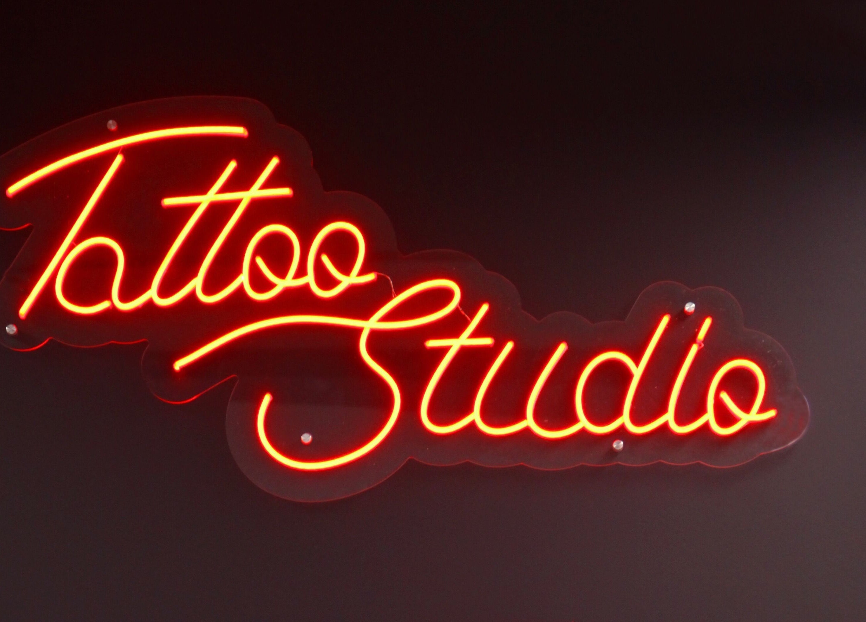 Neon sign at VEAN TATTOO Bristol, Bristol, England, GB, glowing red with 'Tattoo Studio' text.