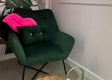 Chic seating corner at LVL Lashes Blackpool, Blackpool, England with a plush green chair and pink cushion.