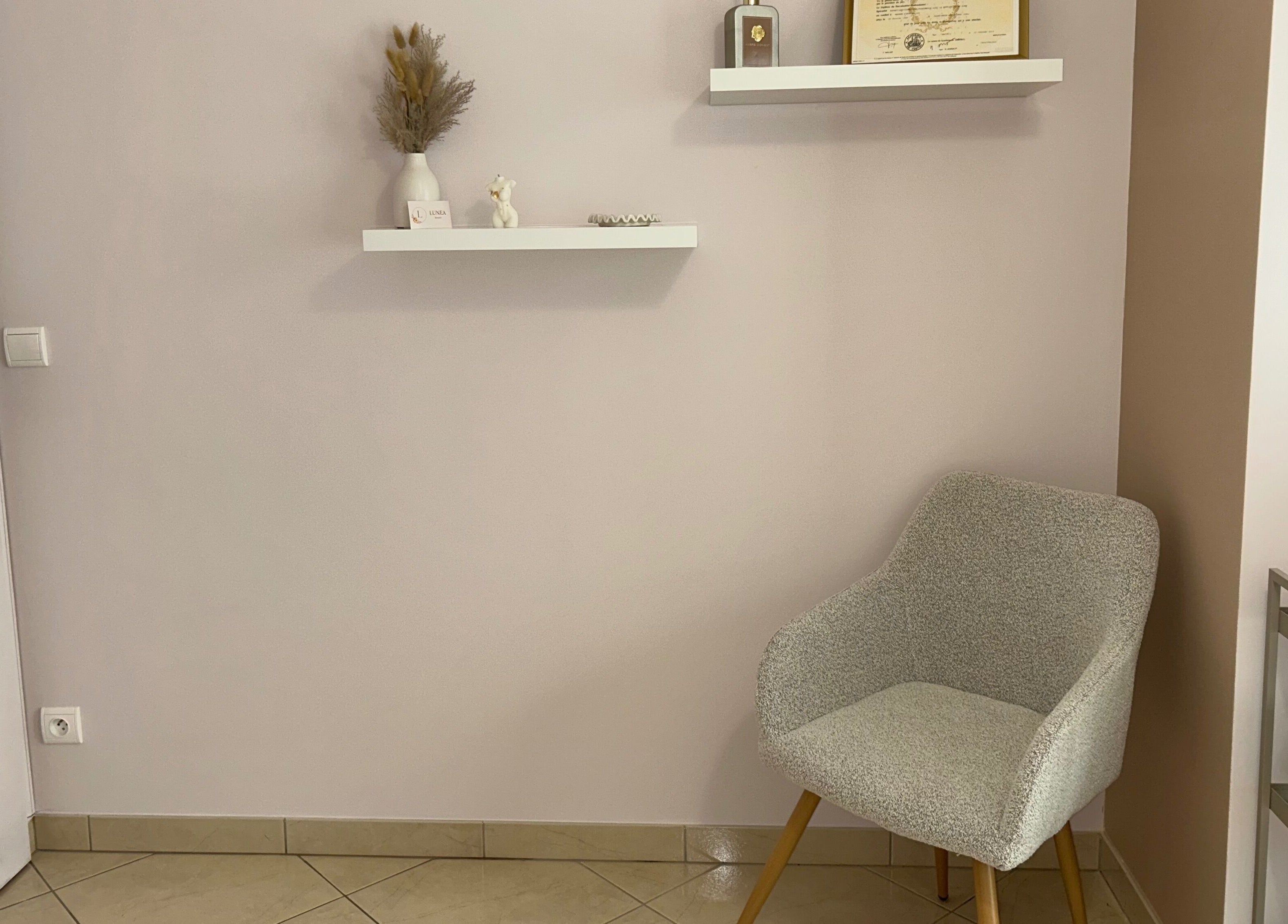 Coin détente à Lunea Beauté, Sucy-en-brie, Île-de-france, FR avec chaise grise et étagères décoratives.