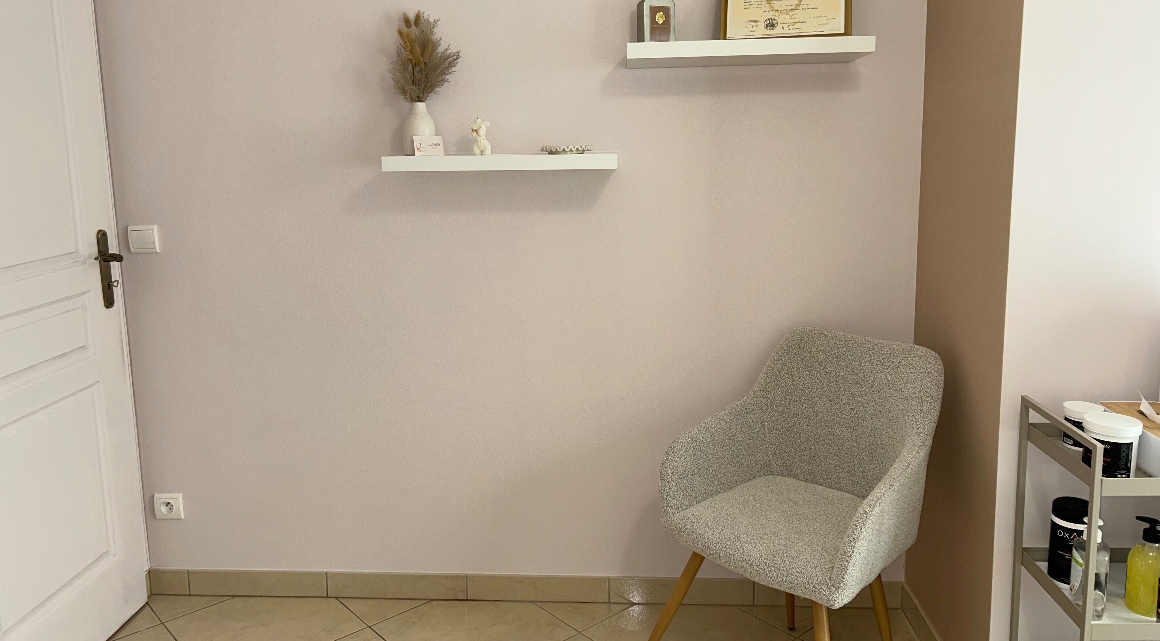 Coin détente à Lunea Beauté, Sucy-en-brie, Île-de-france, FR avec chaise grise et étagères décoratives.