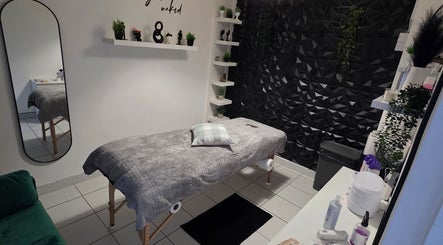 Cozy treatment room at WaxByLora, London, England, GB, with a massage table, plants, and decor.