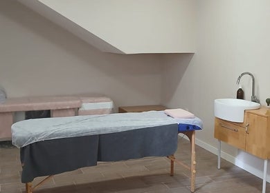 Sala de tratamiento en RAÍCES ESTETICA Y BIENESTAR, Castilla-la Mancha, ES con camilla y lavabo de madera.