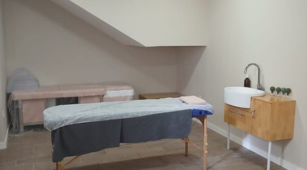 Sala de tratamiento en RAÍCES ESTETICA Y BIENESTAR, Castilla-la Mancha, ES con camilla y lavabo de madera.
