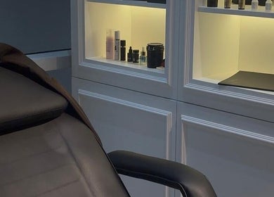 Cabine de soin élégante chez So Chic Paris à Dubai, Dubai, AE avec produits de beauté sur étagères éclairées.