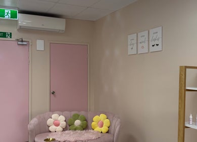 Stylish lounge at Fancy Lashes TSV, Aitkenvale, Queensland, AU, featuring pink accents and floral pillows.