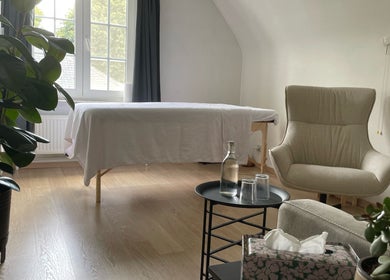Rustige massagekamer bij De Waterlelie, Nazareth-de Pinte, Vlaanderen, BE met comfortabele stoel en plant.