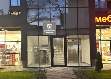 Exterior of Д-р Алимоллова- ендокринолог office in Asenovgrad, Plovdiv, BG with illuminated shops nearby.
