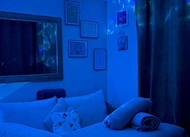 Serene massage room at Bee Elevated Holistic Health in Holbury, England, GB with calming blue lighting.
